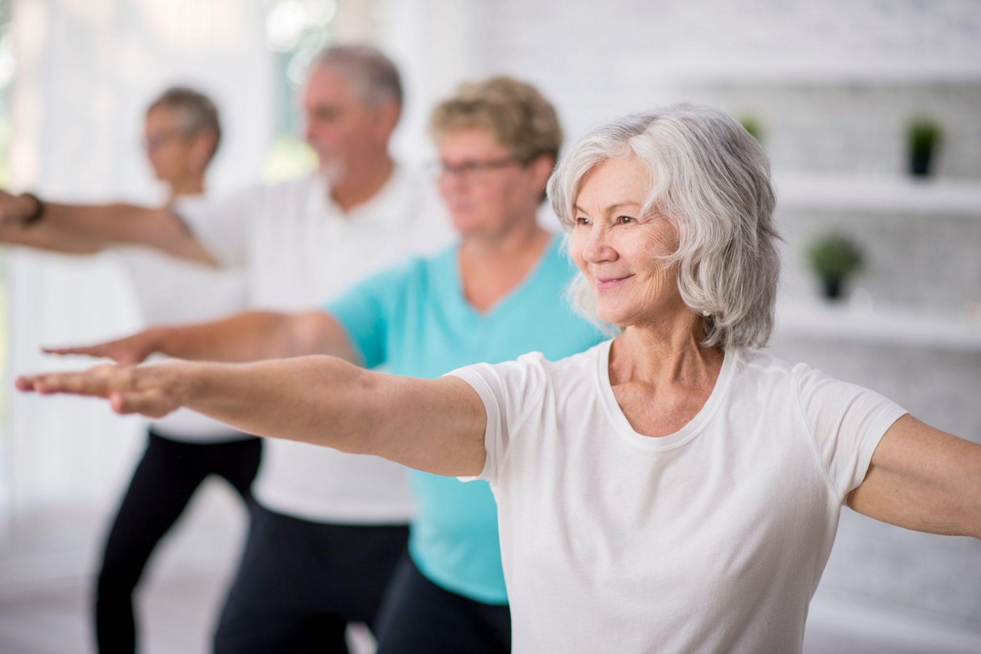 Senior residents in a group exercise class at a bright and modern living communitys fitness room.