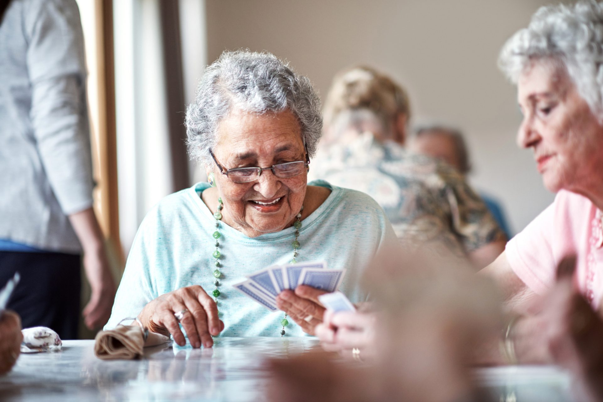 Senior residents enjoying a card game at their community center in a bright and cheerful room.