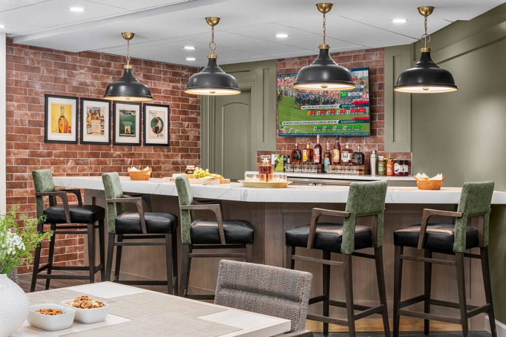 Bar Area in Senior Living Community in Lexington, KY Bar area with green high chairs, wall art, and a TV in a senior living community in Lexington, KY.