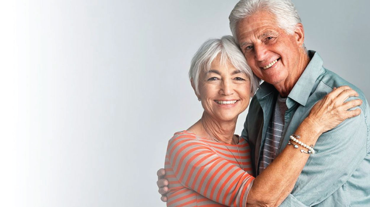 Happy senior couple embracing and smiling in a living community.