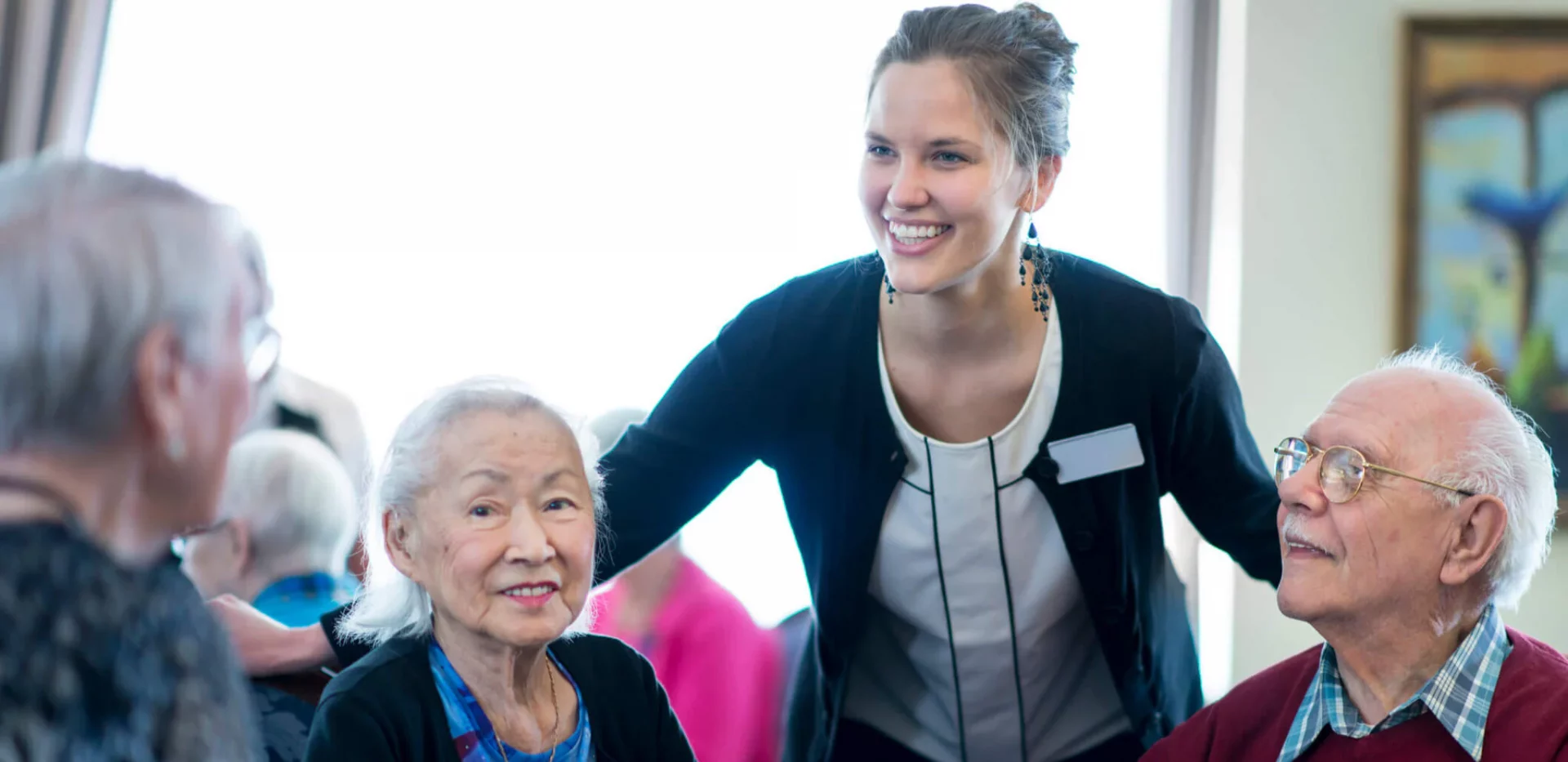 Senior living employee greeting table of seniors