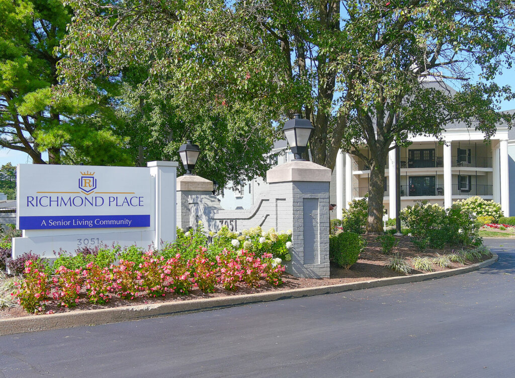 Entrance sign and landscaping of Richmond Place with trees and a main building visible.