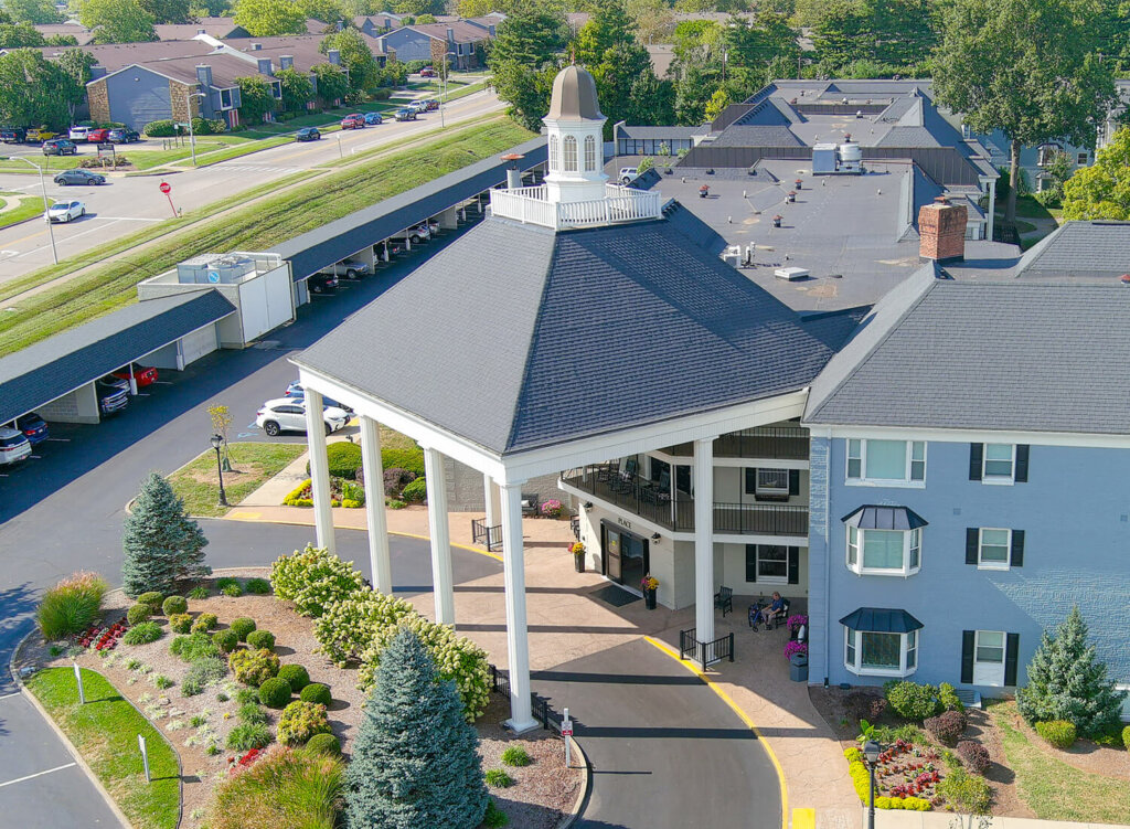Aerial view of a senior community with units, gardens, and a large covered entrance.