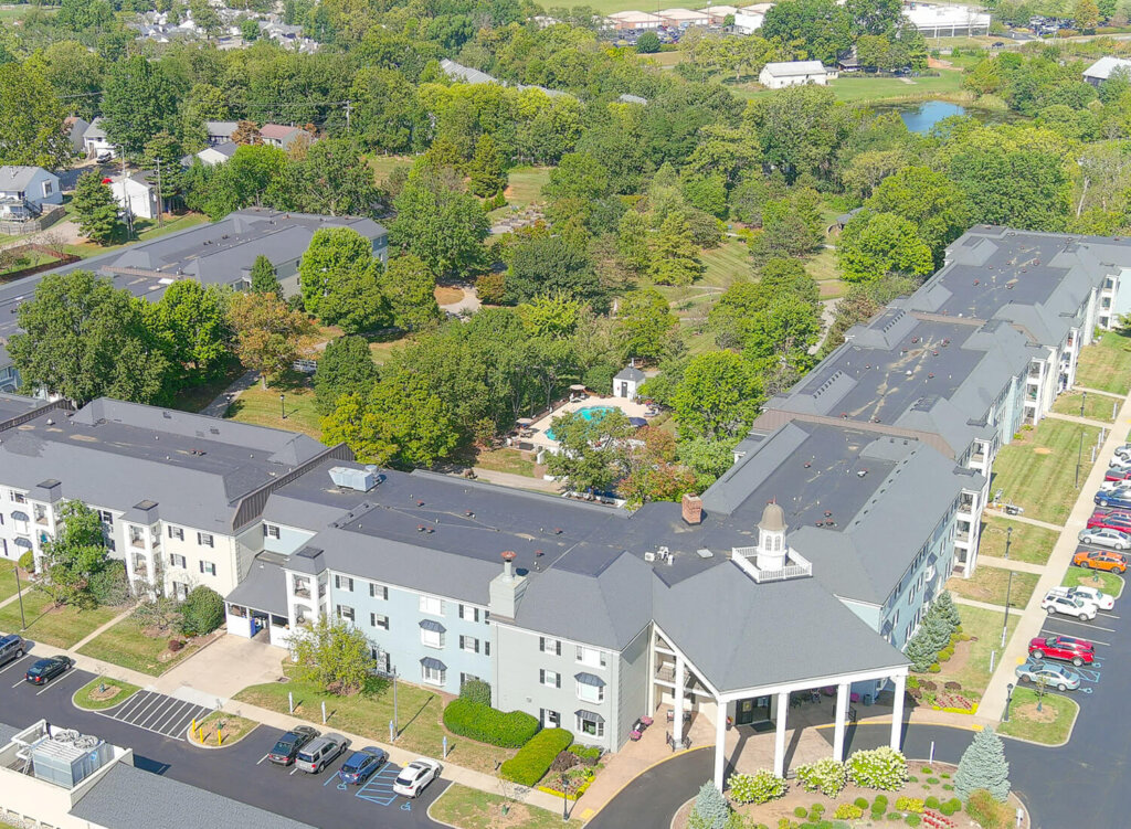 Aerial view of a senior living community with surrounding trees and outdoor pool.