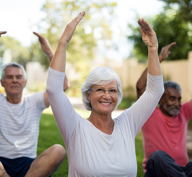 Senior woman doing seated stretches during outdoor exercise class